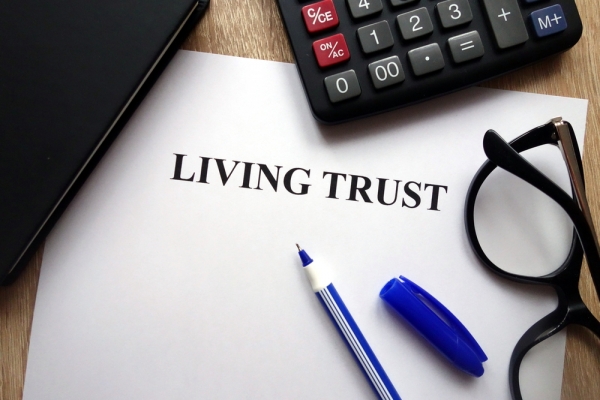 Living trust document, pen, glasses and calculator on desk